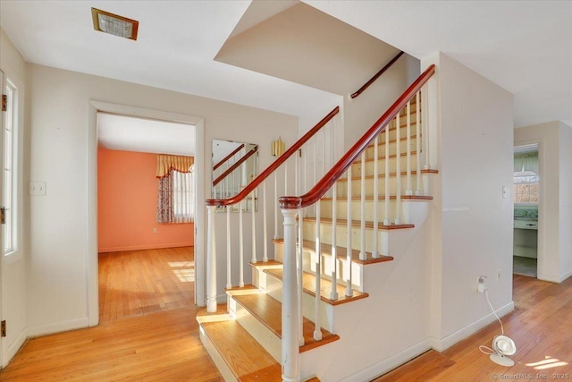 stairway with baseboards, visible vents, and wood finished floors