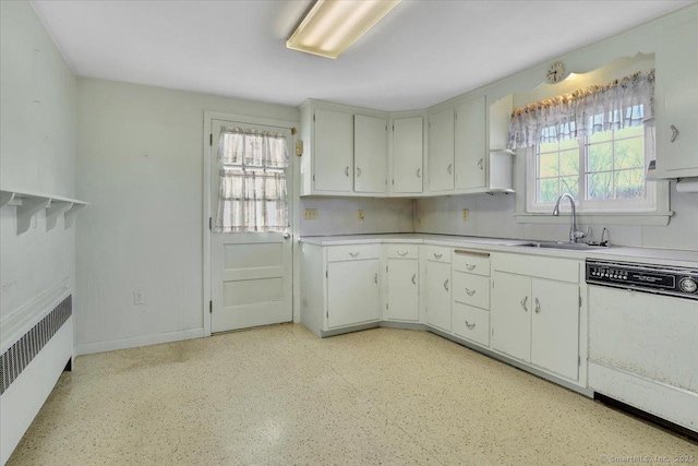 kitchen with white cabinets, radiator heating unit, white dishwasher, light countertops, and a sink