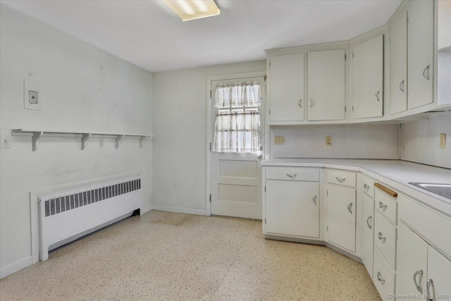 kitchen with radiator, baseboards, white cabinetry, and light countertops