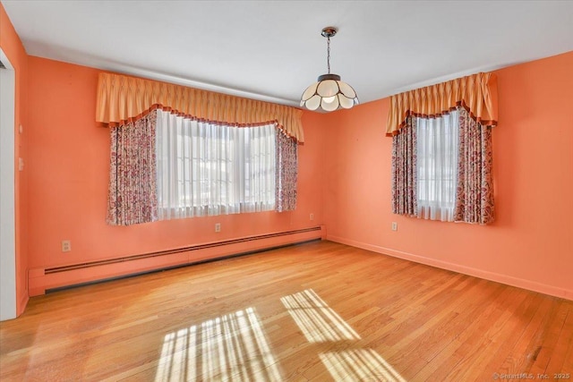 unfurnished room featuring light wood finished floors, baseboards, and a baseboard heating unit