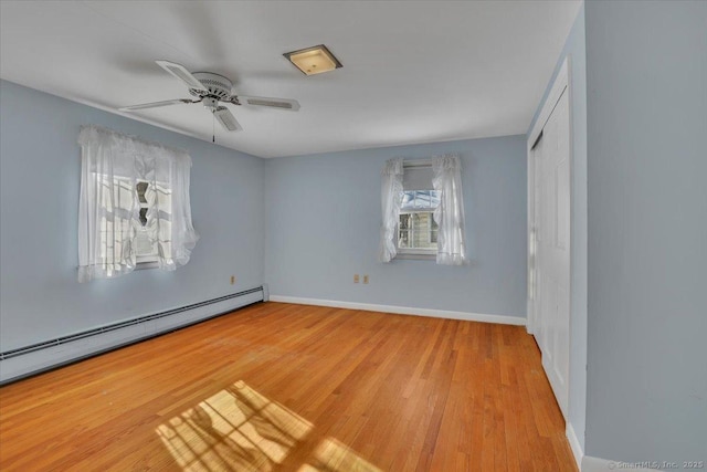 unfurnished bedroom with baseboard heating, light wood-type flooring, a closet, and baseboards