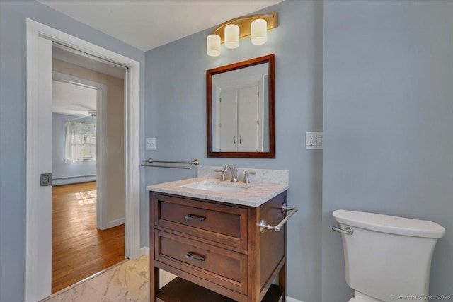 half bathroom featuring baseboards, toilet, marble finish floor, vanity, and a baseboard heating unit