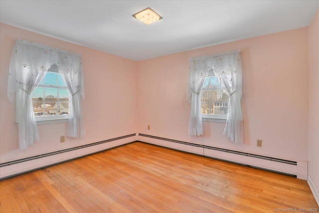 empty room with light wood-type flooring, plenty of natural light, and a baseboard heating unit