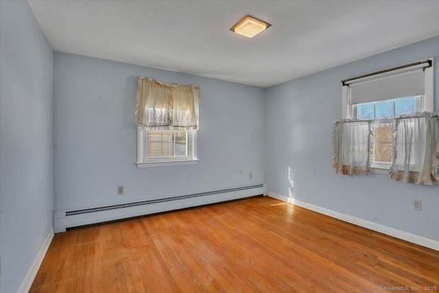 unfurnished room with light wood finished floors, a baseboard radiator, and baseboards