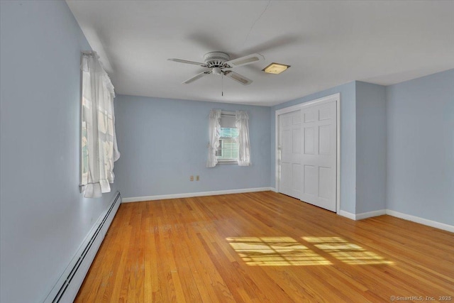 unfurnished bedroom with baseboards, a ceiling fan, a baseboard radiator, light wood-style floors, and a closet