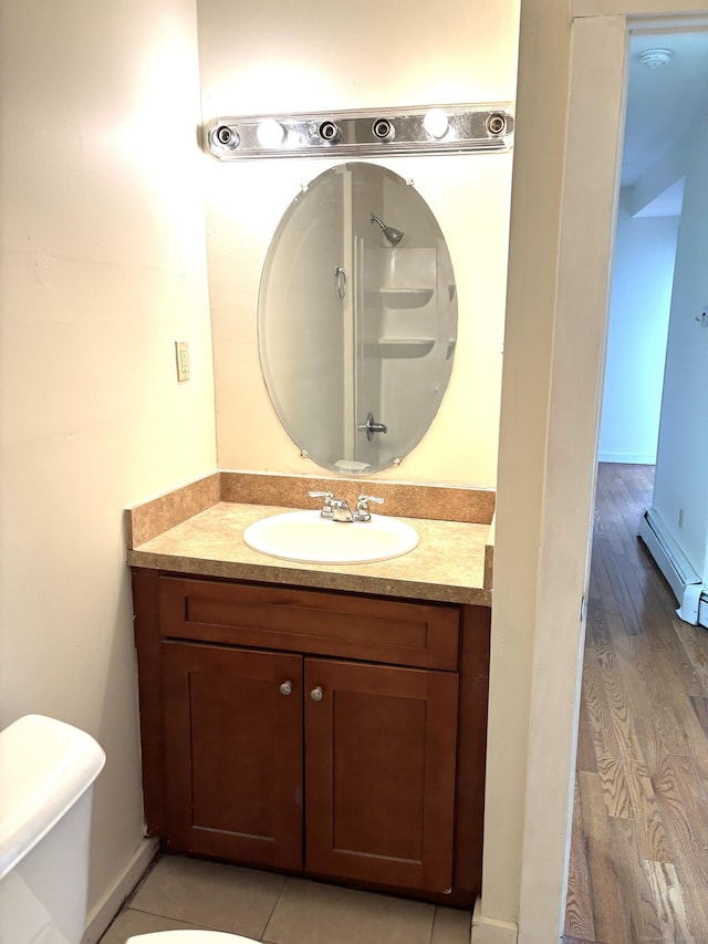 bathroom featuring toilet, a baseboard heating unit, and vanity