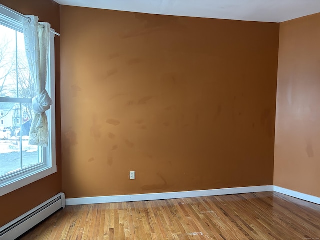 unfurnished room featuring baseboard heating, light wood-type flooring, and baseboards