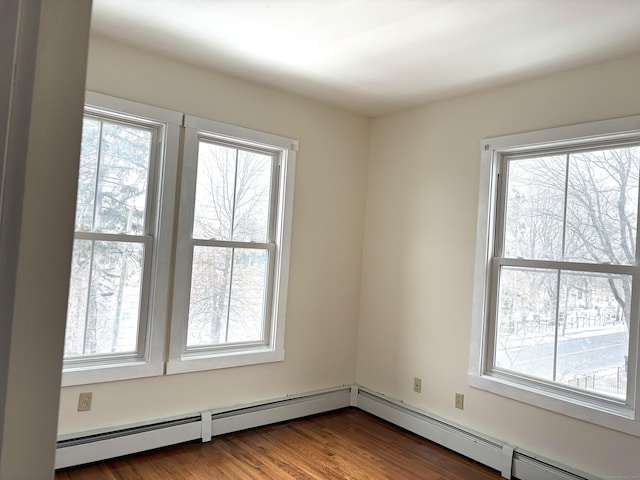 spare room featuring baseboard heating and wood finished floors