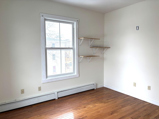 spare room with a baseboard heating unit, hardwood / wood-style floors, and baseboards