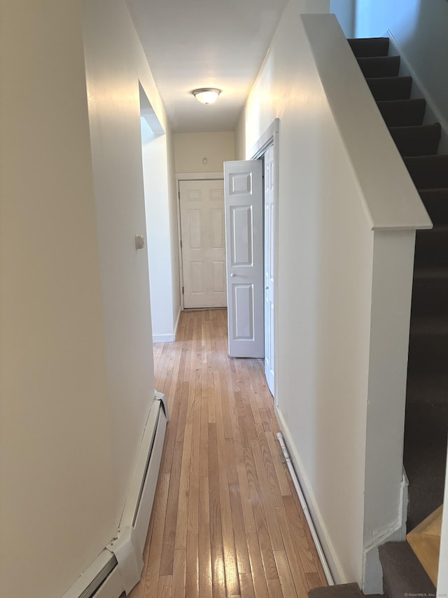 hall featuring light wood finished floors, stairs, and baseboards