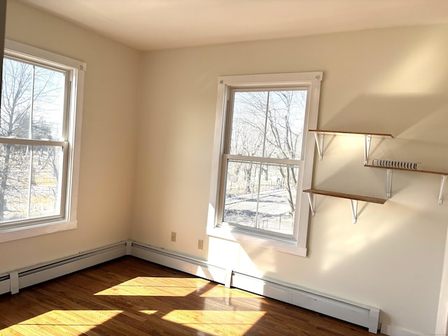 spare room with baseboard heating and wood finished floors