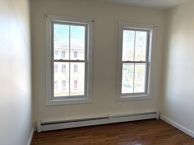 empty room with baseboards, baseboard heating, and wood finished floors