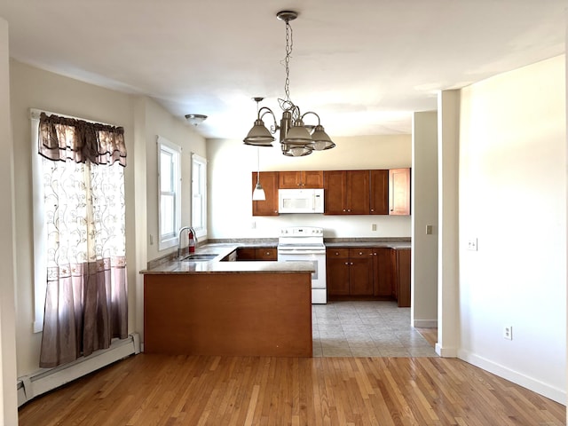 kitchen featuring a peninsula, white appliances, a sink, light wood-style floors, and baseboard heating