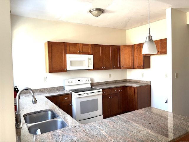 kitchen featuring pendant lighting, white appliances, a sink, and dark stone countertops