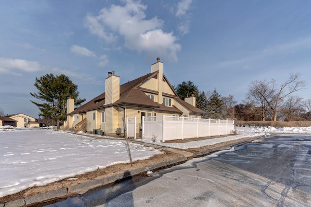 view of snowy exterior featuring a chimney and fence