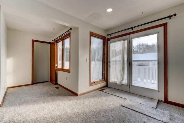 interior space with light carpet, plenty of natural light, and baseboards