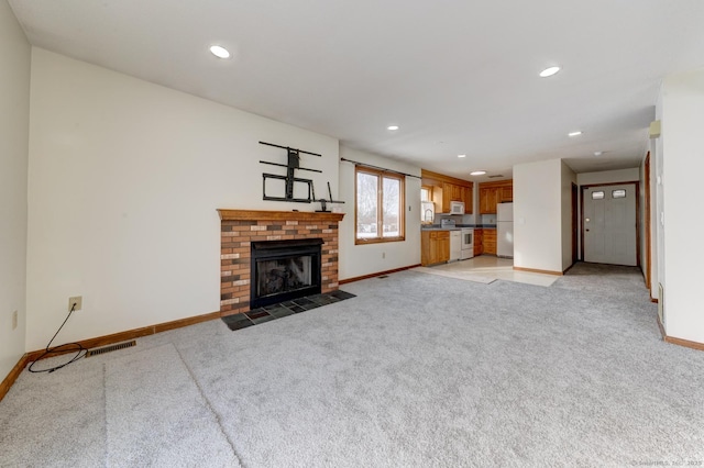 unfurnished living room with baseboards, a fireplace, visible vents, and light colored carpet