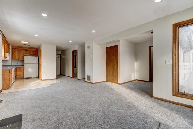 unfurnished living room with light carpet, recessed lighting, and baseboards