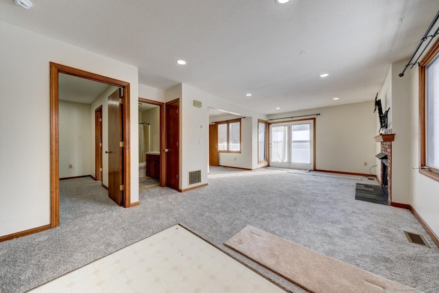 unfurnished living room with light carpet, a fireplace, visible vents, and baseboards