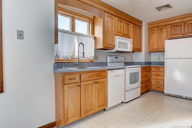 kitchen with light floors, visible vents, brown cabinetry, a sink, and white appliances