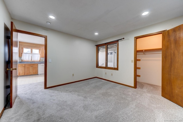 unfurnished bedroom with recessed lighting, light colored carpet, a sink, and a spacious closet