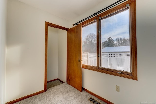 unfurnished room featuring light colored carpet, visible vents, and baseboards