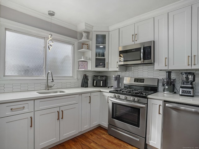 kitchen featuring appliances with stainless steel finishes, wood finished floors, light countertops, open shelves, and a sink