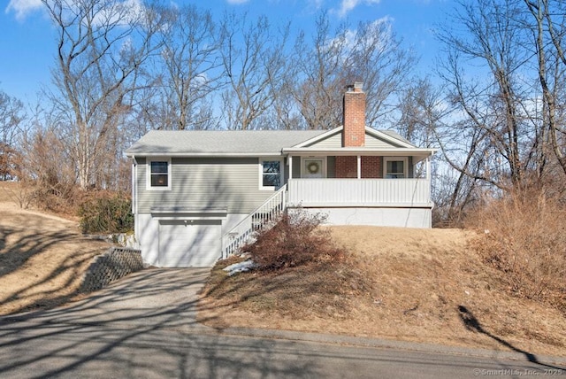 ranch-style house featuring a porch, a garage, driveway, stairway, and a chimney