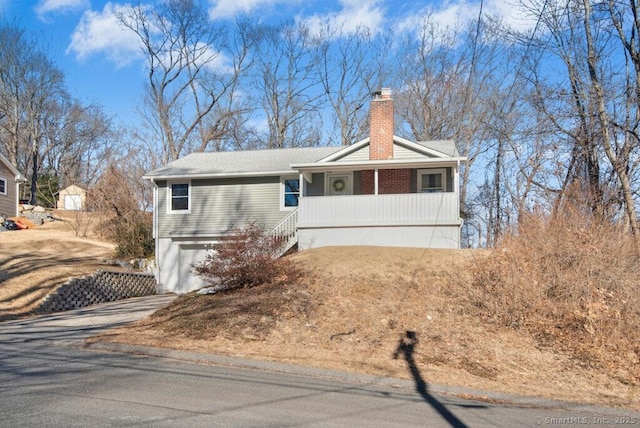 single story home featuring driveway, a chimney, and an attached garage