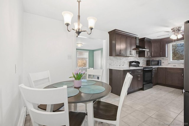 dining space featuring light tile patterned floors, ceiling fan with notable chandelier, and a healthy amount of sunlight