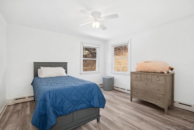 bedroom with a baseboard heating unit, baseboard heating, wood finished floors, and a ceiling fan