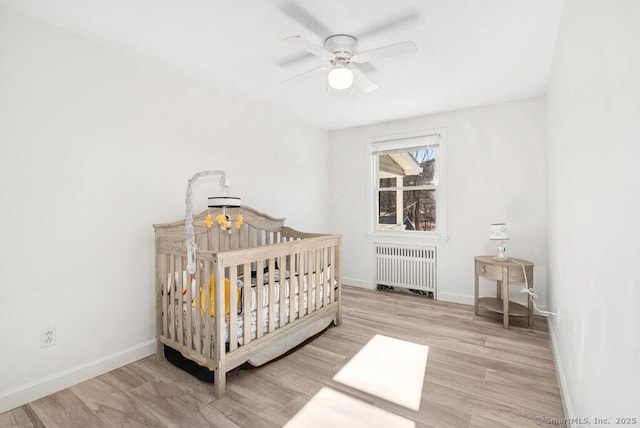 bedroom with baseboards, radiator heating unit, and wood finished floors