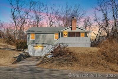 view of front of property featuring a porch, a garage, driveway, stairway, and a chimney