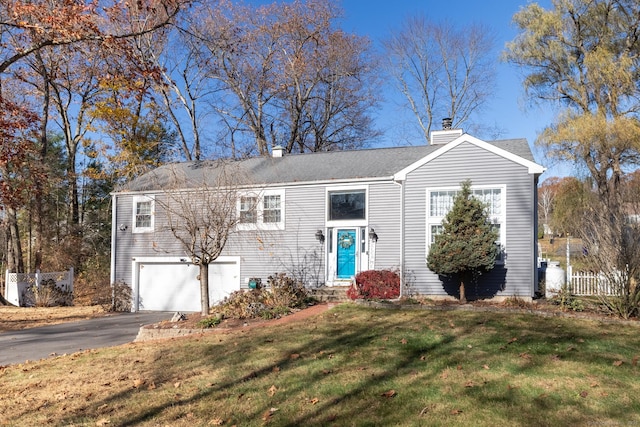 raised ranch with aphalt driveway, a garage, fence, a chimney, and a front yard