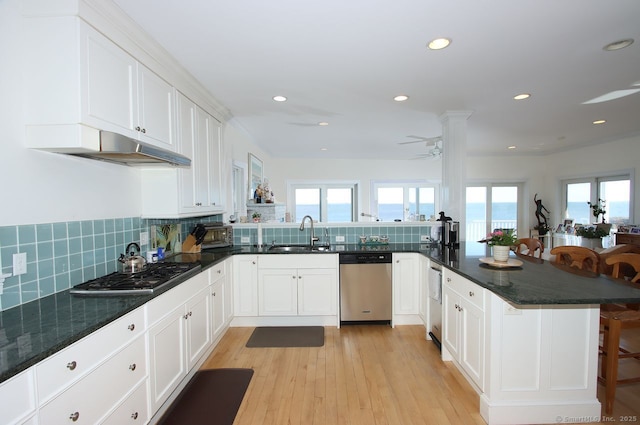 kitchen featuring a peninsula, white cabinetry, appliances with stainless steel finishes, and a sink