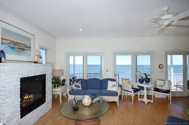 living area featuring a brick fireplace, a water view, and wood finished floors