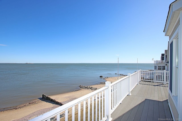 wooden deck featuring a water view and a view of the beach