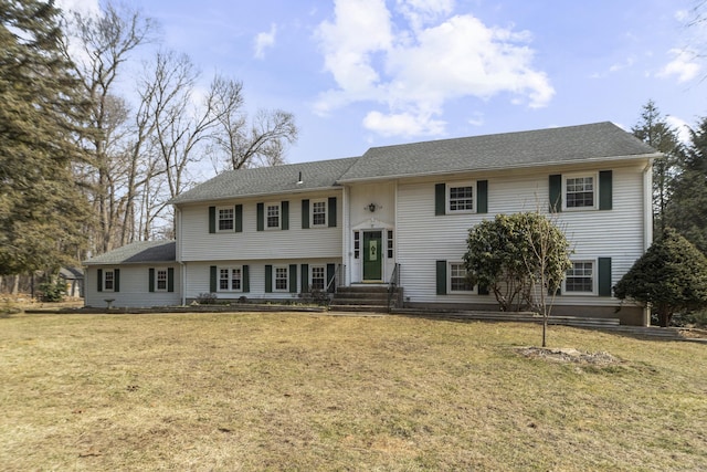 bi-level home featuring entry steps, a front lawn, and a shingled roof