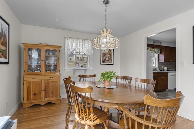 dining area with baseboards and light wood finished floors