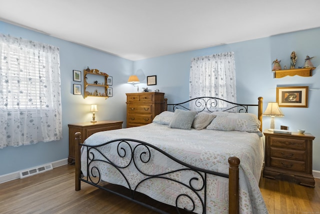 bedroom with visible vents, baseboards, and wood finished floors