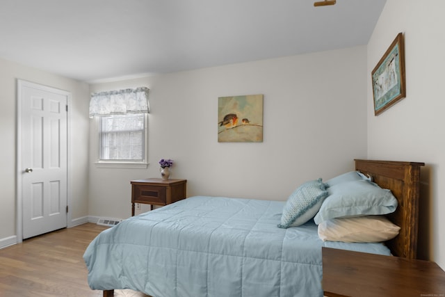 bedroom with wood finished floors, visible vents, and baseboards