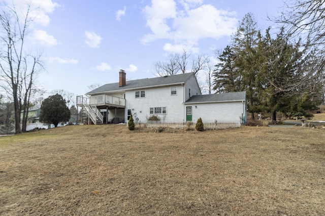 rear view of property featuring a lawn, a chimney, a wooden deck, and stairs