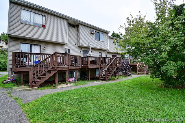 rear view of property with stairway, a deck, and a lawn