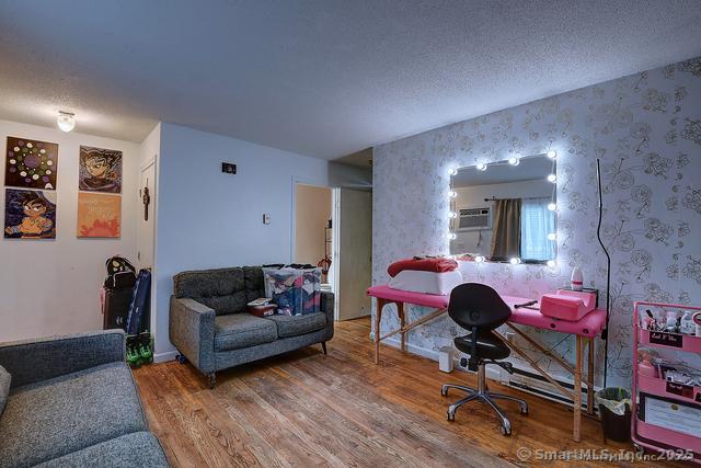 office with wood finished floors, a textured ceiling, and wallpapered walls