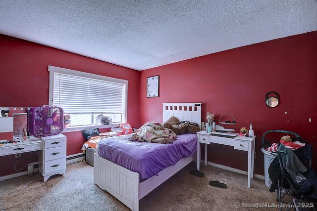 bedroom featuring a textured ceiling, a baseboard radiator, and light colored carpet