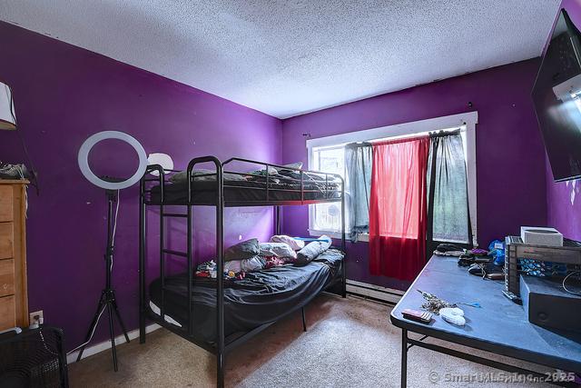 bedroom featuring carpet floors, a baseboard radiator, and a textured ceiling