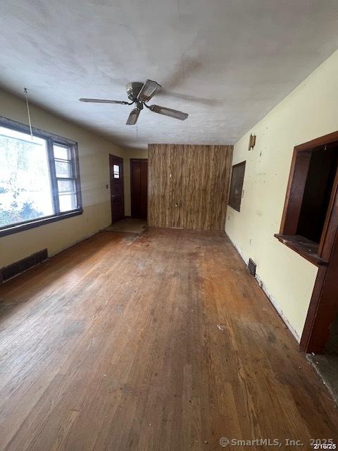 unfurnished living room featuring a ceiling fan, dark wood-style flooring, and visible vents