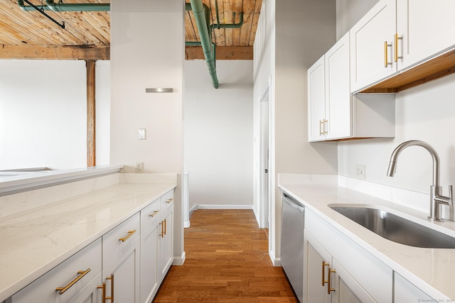 kitchen featuring stainless steel dishwasher, white cabinetry, light stone counters, and a sink