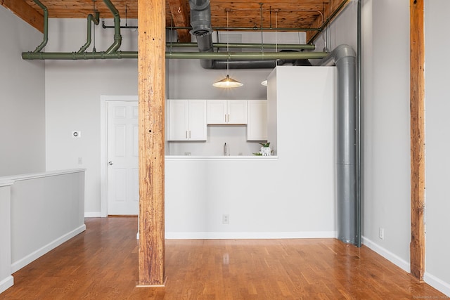 kitchen featuring baseboards, a high ceiling, wood finished floors, and white cabinets