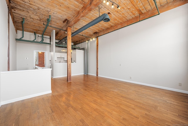 unfurnished room with beamed ceiling, wooden ceiling, wood finished floors, and baseboards